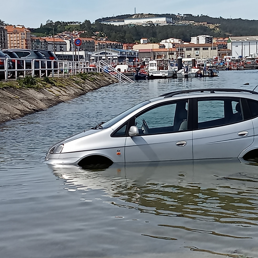 Un nuevo coche aparcado en la rampa de varada del puerto de Ribeira fue alcanzado por el agua al subir la marea